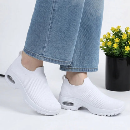 HexoComfy™ Men's Orthopedic Slip-On Shoes in White worn with rolled jeans beside a potted plant
